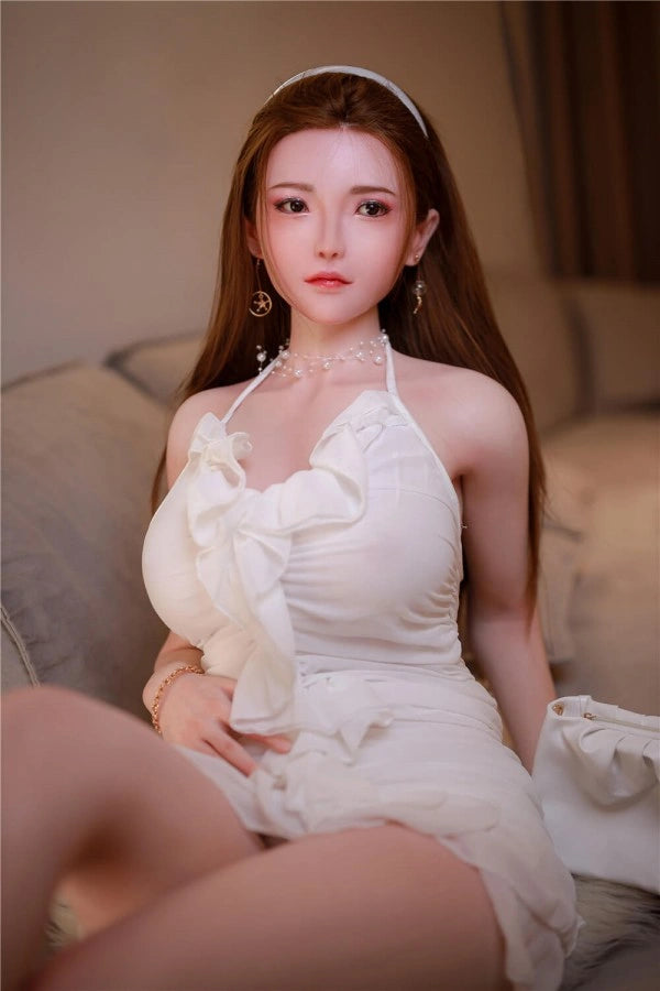 Sexpuppe in weißem Kleid sitzend