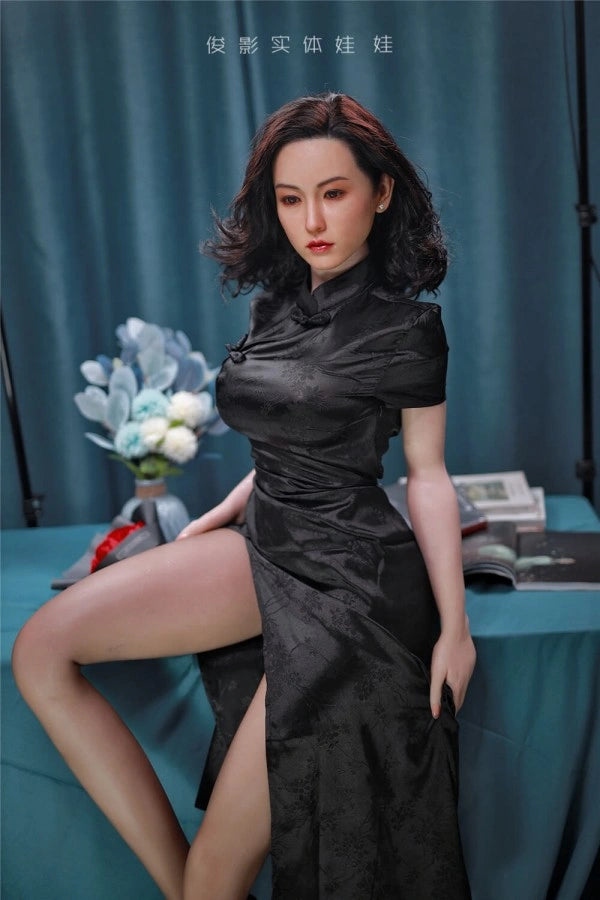 Sexpuppe in schwarzem Kleid sitzend