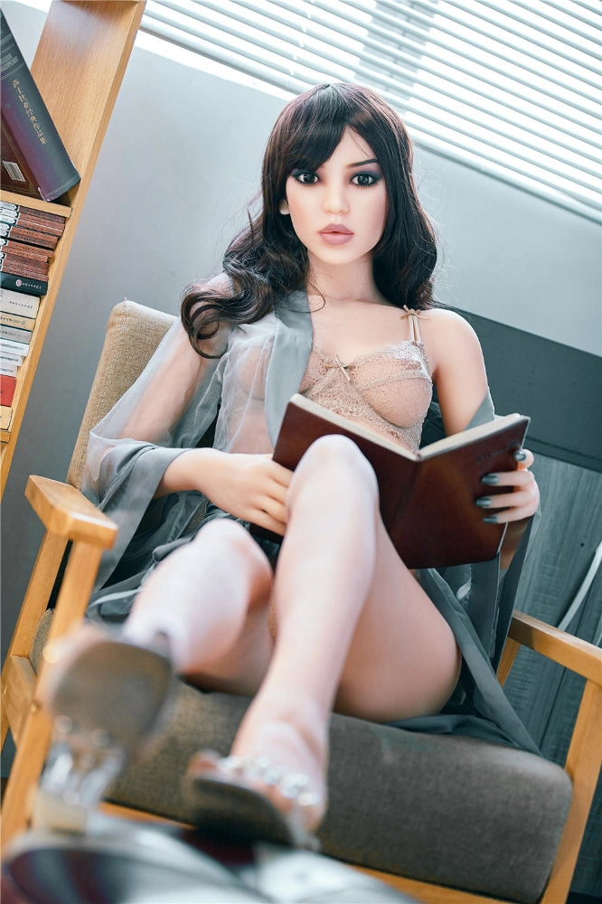 Sexpuppe liest Buch im Sessel