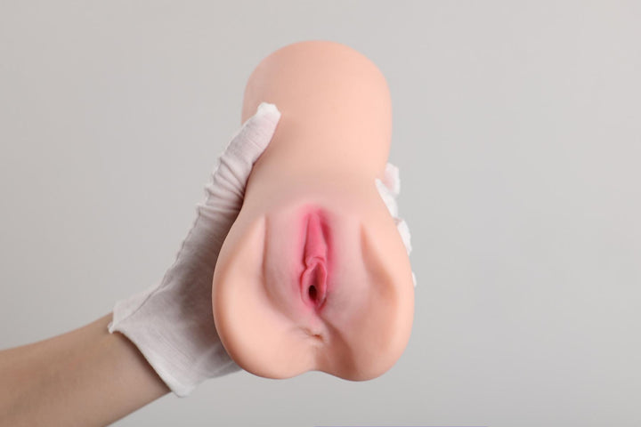 Hand hält realistische Sexspielzeug-Puppe