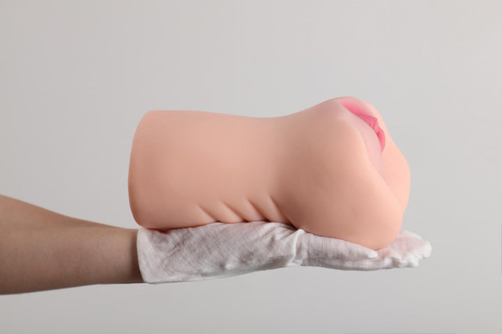 Hand hält realistische Sexspielzeug-Puppe