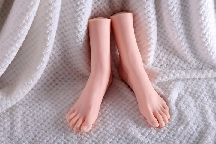 Sexpuppen-Füße auf weißem Stoff